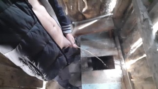 Russischer Typ pisst in eine rustikale Toilette