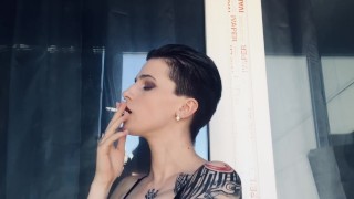 ragazza calda in rossetto rosso fumo sul balcone solo in reggiseno