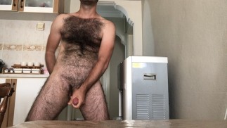 Homem solo muito peludo goza na mesa da cozinha enquanto fuma e toma chá