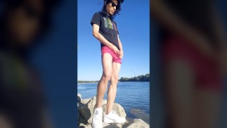 Minet garçon aux longs cheveux noirs pissant pipi sur le fleuve vêtu de lunettes casquette baskets