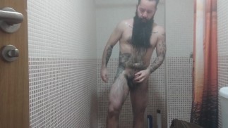 Solo masculino. Urso barbudo e tatuado no chuveiro
