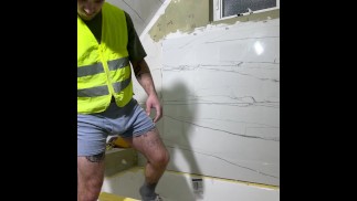 Napalone pracownik budowlany instaluje płytkę z wybrzuszeniem