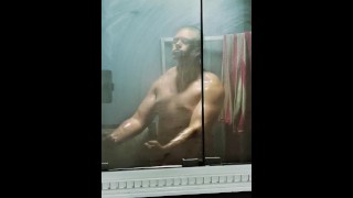 Bodybuilder auf einem Bulk-Flex im nebligen Spiegel vor dem Duschen