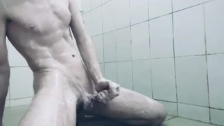 一个大鸡巴的年轻人在公共淋浴间刮胡子和手淫