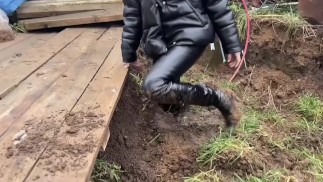 Девушка в сапогах на высоком каблуке любит пачкаться в грязи, пачкает сапоги по колено,