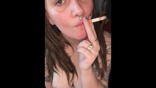 Une brune fumeuse joue avec ses seins
